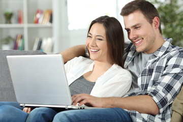 Couple checking online content in a laptop sitting at home