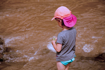 Little girl having fun by  mountain  river at summer (Holiday, rest, happy childhood, games, nature concept)