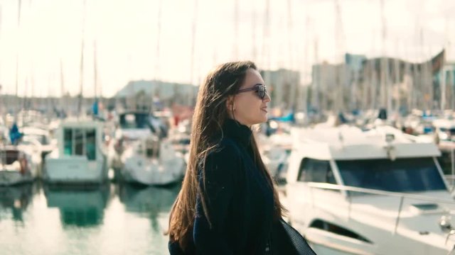 Woman in sunglasses walking with a lot of yachts and boats behind. Slow motion - Powered by Adobe