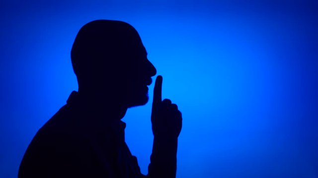 Silhouette of senior man on blue background. Male's face in profile put finger to lips making silence gesture. Black contur shadow of grandfather's half-face shush. Concept of mystery and secrecy