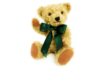 Cute teddy bear is sitting with raise paw, toy is made from golden mohair complemented with pure wool
