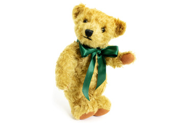 Cute teddy bear is standing with raised paw, toy is made from golden mohair complemented with pure wool