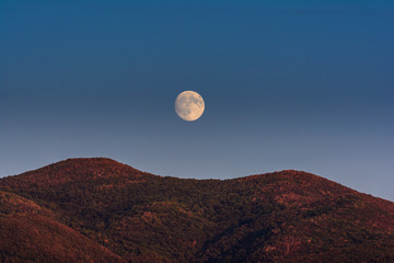 Mond über symmetrischen Hügeln in der Toskana am Abend