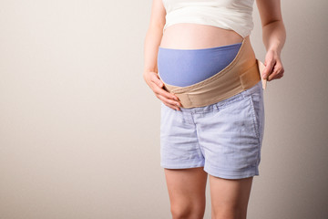 Young pregnant woman with orthopedic support belt