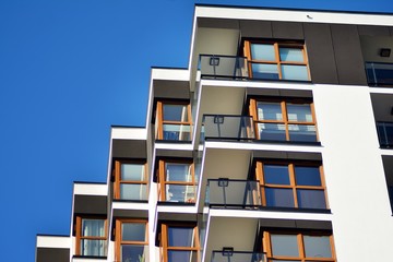  Fragment of a facade of a building with windows and balconies. Modern home with many flats.