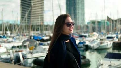 Woman in sunglasses walking with a lot of yachts and boats behind. Slow motion