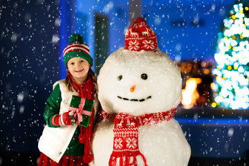 Kids and snowman in garden at Christmas fireplace.