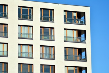  Fragment of a facade of a building with windows and balconies. Modern home with many flats.