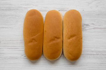 Fresh hot dog buns on white wooden background, overhead view. Flat lay, from above, top view. Closeup.