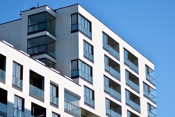  Fragment of a facade of a building with windows and balconies. Modern home with many flats.