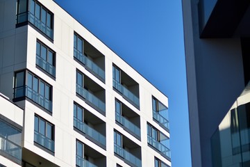  Fragment of a facade of a building with windows and balconies. Modern home with many flats.