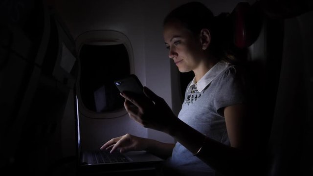 Businesswoman working on notebook in dark airplane salon near window