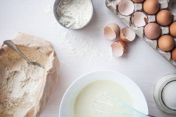 Ingredients for baking cake laid out on a white wooden table. selective focus