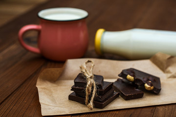 Handmade chocolate, cup and bottle with milk on a wooden background.