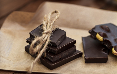 Handmade pieces of chocolate on rustic paper close-up.