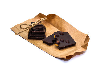 Slices of handmade chocolate on rustic paper closeup isolated on white background.