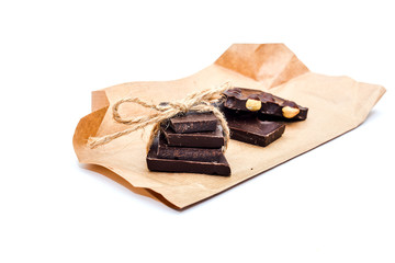 Slices of handmade chocolate on rustic paper closeup isolated on white background.