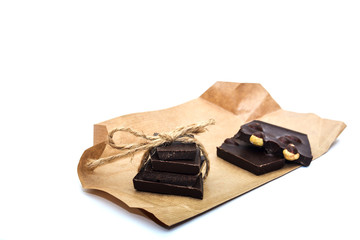 Slices of handmade chocolate on rustic paper closeup isolated on white background.