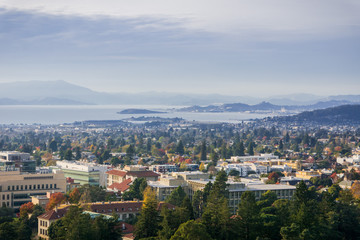 View towards Berkeley and Richmond on a sunny but hazy autumn day; University of California campus buildings in the foreground, San Francisco bay area, California