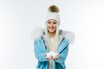Attractive young caucasian woman in warm clothing, coat with fur hod smiling with snowball. White...