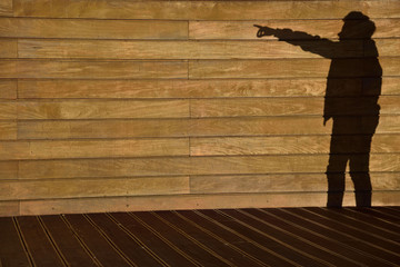 Teenager's shadow on a background of a wall from a wooden paneling.