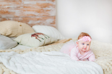 Fototapeta na wymiar a little girl with blue eyes lying on the bed near the pillows. Pink bandage on the head in a beautiful girl