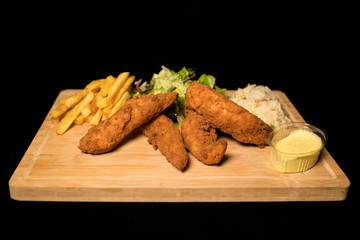 Chicken Goujons served with rice, salad and french friends on wood