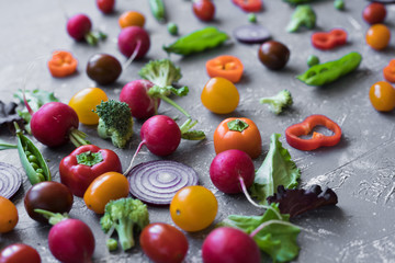 Obraz na płótnie Canvas Fresh organic vegetables close up. Radish, green peas, broccoli, tomato and onion on grey background. 