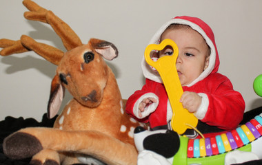 nine months old baby boy in santa clause suit with dear and toys