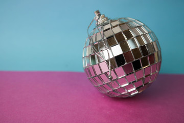 Silver mirror musical club disco ball small round glass winter shiny decorative beautiful xmas festive Christmas ball, Christmas toy plastered on glitter on a gray pink purple background