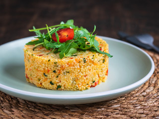 Delicious Vegetarian Couscous Tabbouleh salad with vegetables, decorated with arugula and cherry tomato.