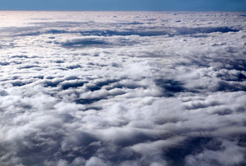 The plane flies high above the clouds. View from the window. Sunny day. Nature Background. Travel concept.