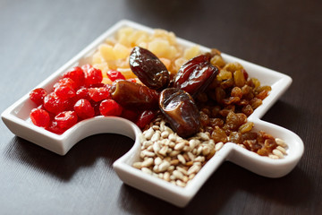 Dried fruits, seeds, raisins, dates, in a white porcelain dish on a table