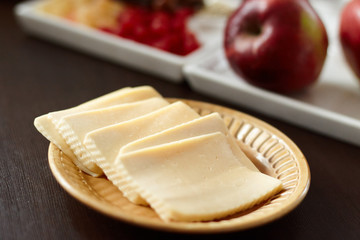 Sliced cheese in a beautiful porcelain plate of yellow color