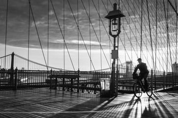 Bicyclist on Brooklyn Bridge during sunrise in New York. USA
