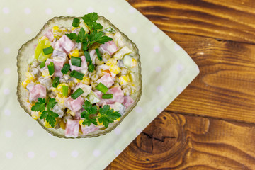 Tasty salad with sausage, green pea, canned corn, bell pepper, cucumber and mayonnaise on wooden table. Top view