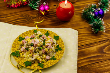Tasty festive salad, Christmas decor and candle on wooden table