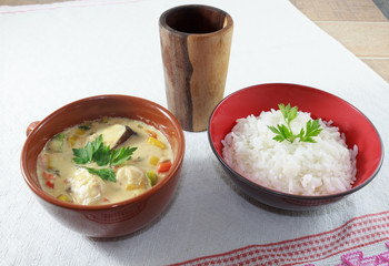 Moqueca of fish and bell peppers, food Brazilian, served with white rice, on a wooden table.