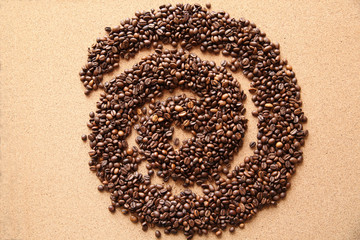 coffee beans laid out on a wooden table in the form of a spiral