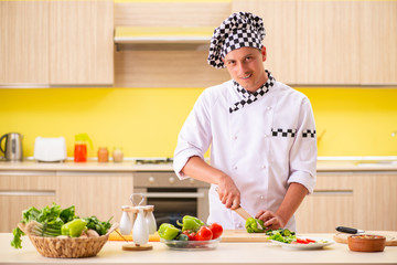 Young professional cook preparing salad at kitchen