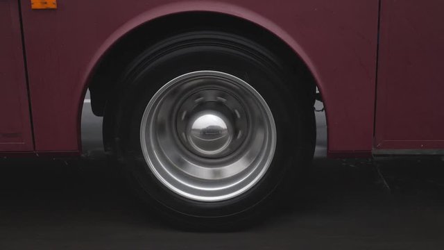 RV wheel in slow motion on wet and rainy highway. Water drops. Purple vehicle.
