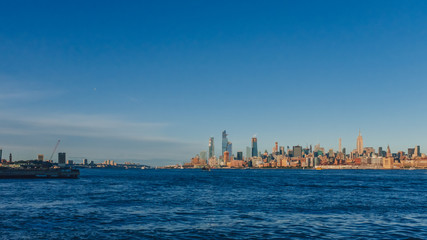 Fototapeta premium Skyline of uptown Manhattan over Hudson River under blue sky, at sunset, in New York City, USA