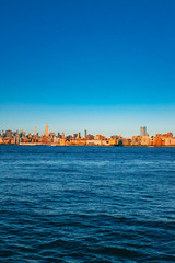 Naklejka premium Skyline of midtown Manhattan over Hudson River under blue sky, at sunset, in New York City, USA