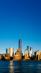 Fototapeta na wymiar Skyline of downtown Manhattan over Hudson River under blue sky, at sunset, in New York City, USA