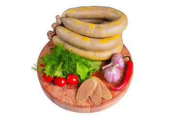 Sausage of liver on a round wooden board with vegetables and greens on white isolated background