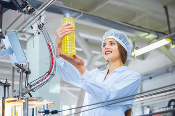 Young beautiful girl in white overalls at the plant for the production of sunflower and olive oil. Quality control in production