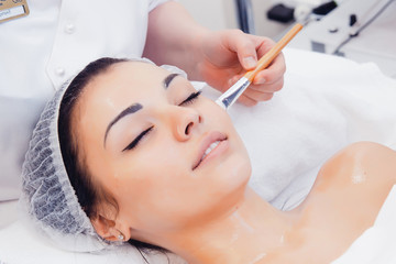 Face Skin Care. Beautician Applying Beauty Oil Mask On Face Using Brush In Spa Salon. Closeup Of...