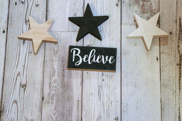 Rustic Christmas holiday flatlay with wood stars, and a black and white Believel word on wood background