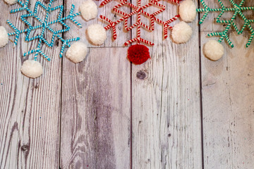 Pom pom twine fabric snowflakes in white, red, and teal colors. Wood background, useful for rustic Christmas holiday projects