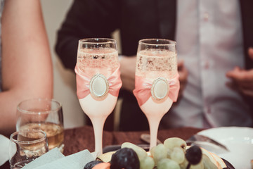 two wedding glasses decorated with beautiful white beads stand near the bride and groom